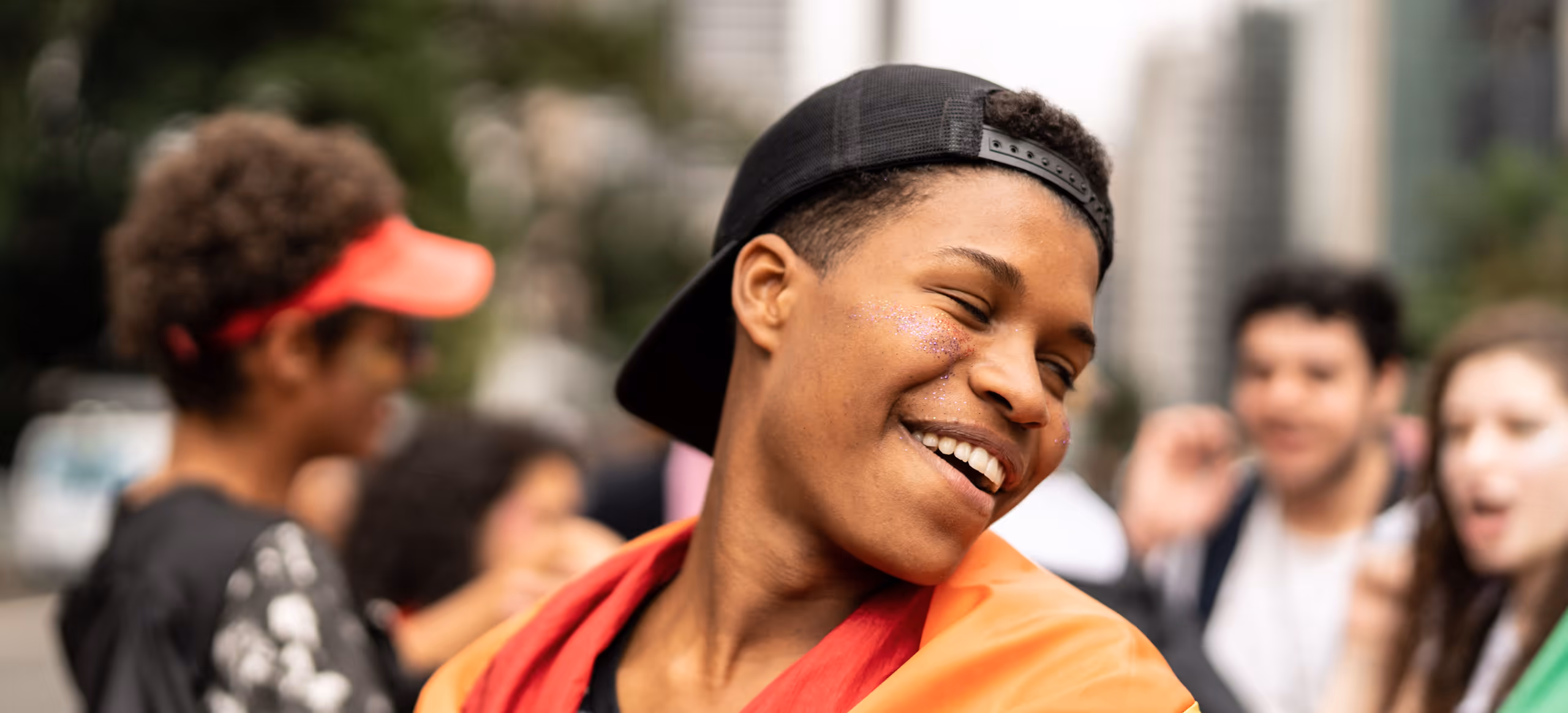 A young person wrapped in a rainbow flag smiling at a Pride event