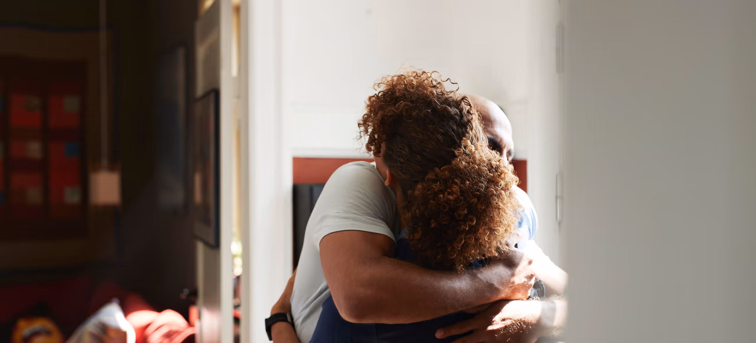 Two people holding each other in a long embrace in a doorway