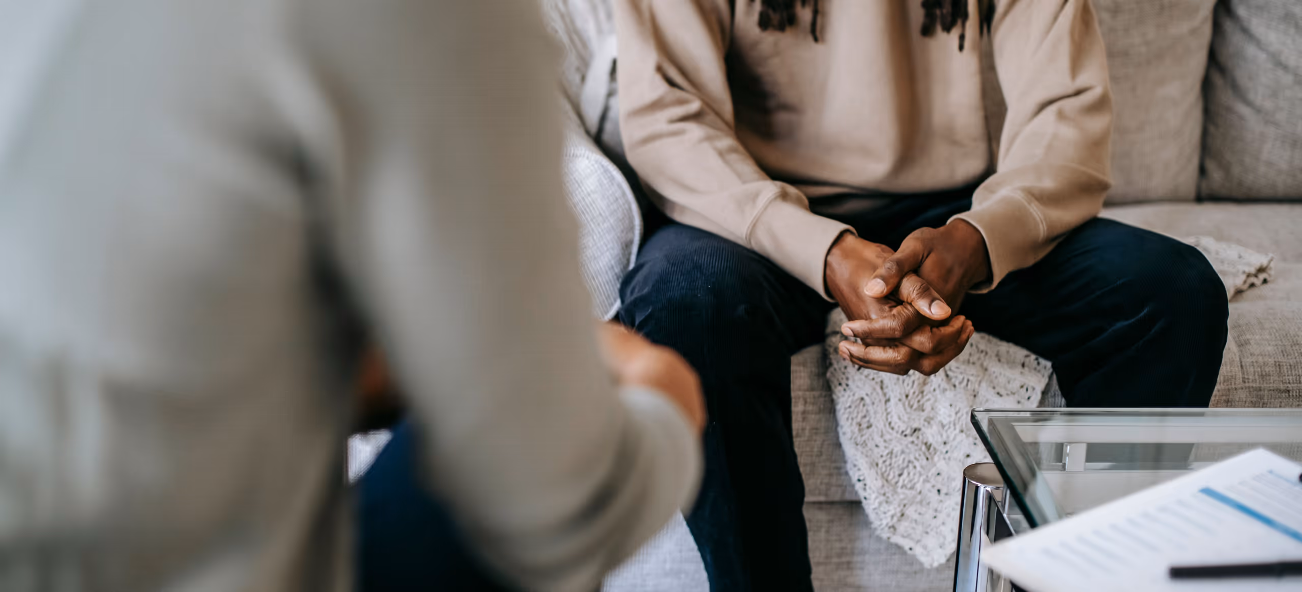 Two people seated across from each other in a quiet session, hands clasped, faces out of frame